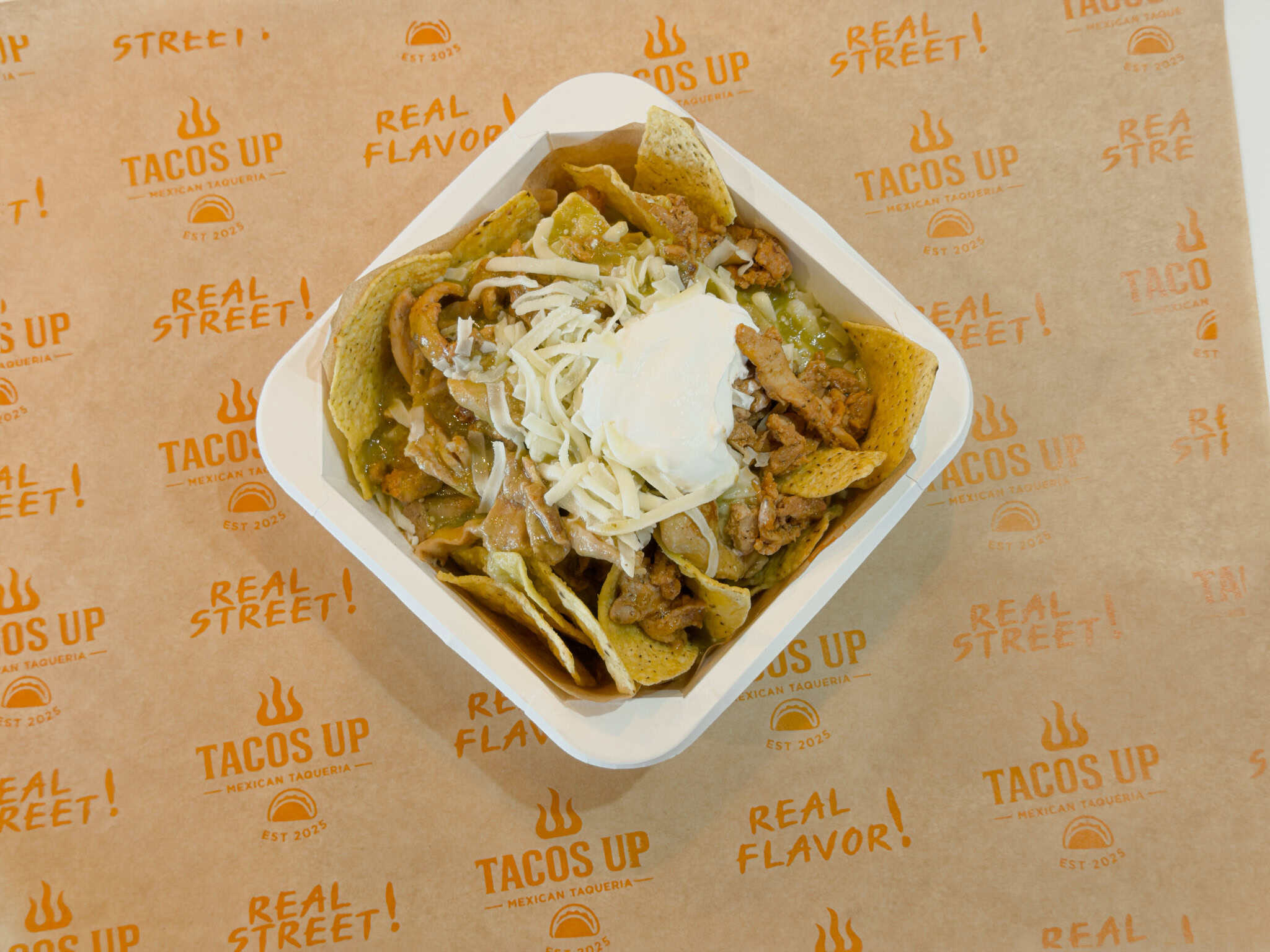 Plate of chilaquiles topped with crema, onion, and cilantro
